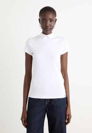 Witte polo met korte mouwen en een klassieke kraag, gemaakt van soepel materiaal, gecombineerd met donkerdenim jeans met een rechte snit.