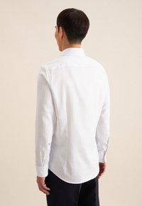 Witte shirt met fijne blauwe strepen, lange mouwen, knoopmanchetten en een klassieke kraag. De achterkant toont een ronde zoom en een gladde textuur.