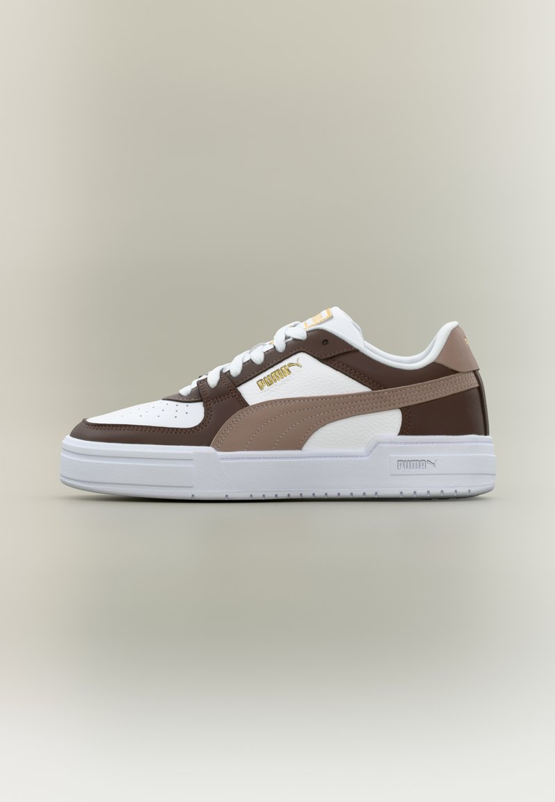 Χαμηλό αθλητικό παπούτσι με πάνελ σε λευκό, καφέ και μπεζ χρώμα, λευκά κορδόνια και χρυσό λογότυπο Puma στο πλάι και στη γλώσσα του παπουτσιού.