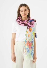 Écharpe colorée avec une base rose, des taches brunes et des motifs floraux vibrants en bleu, vert, orange et rouge. Tissu léger et texturé.