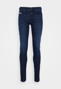 Jeans de mezclilla azul oscuro con corte ajustado, diseño de cinco bolsillos y cierre de botón metálico. Presentan costuras sutiles y una etiqueta de marca.