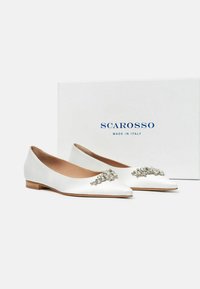 Bailarinas de satén blanco con punta afilada, adornadas con un broche de cristal plateado en la parte delantera, acompañadas de una caja blanca etiquetada "Scarosso".