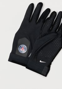 Fekete sportkesztyűk, texturált felülettel, Párizs Saint-Germain logóval és Nike pipa emblémával a mandzsettán. Melegen tartásra és tapadásra tervezték.