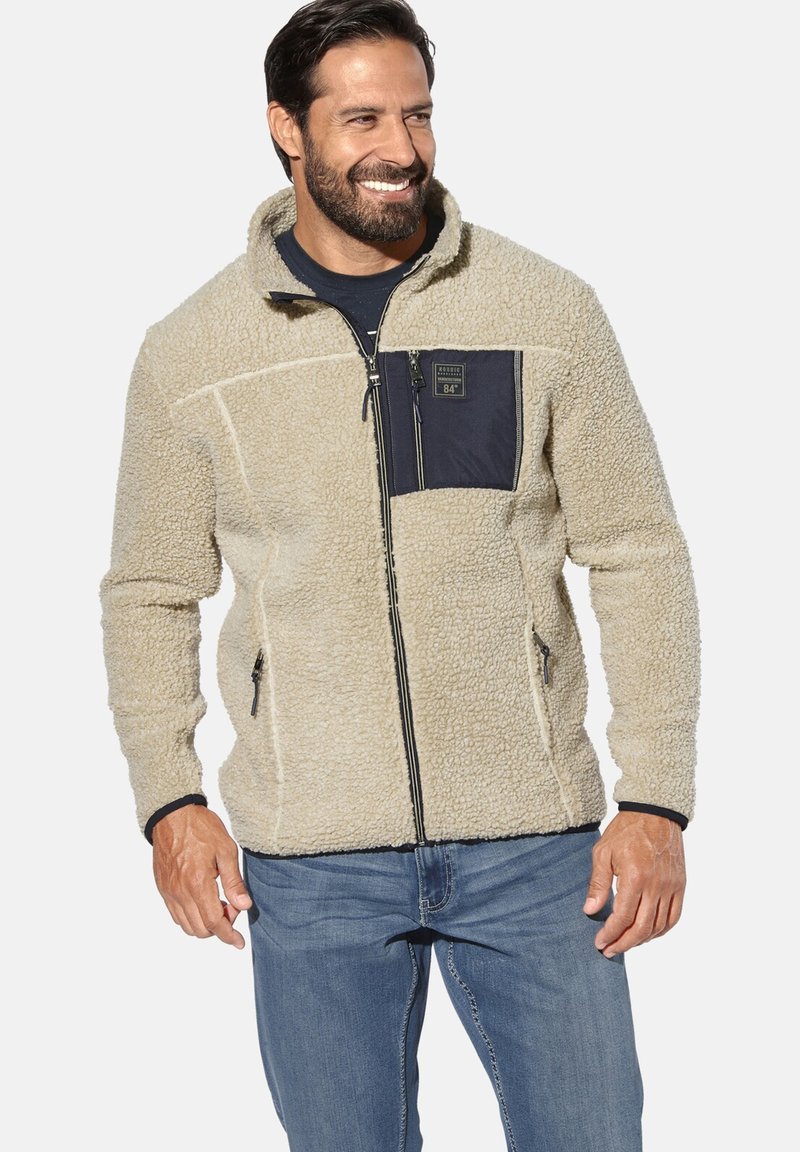 Beige fleece jacket with a black zippered chest pocket, front zip closure, and contrasting black trim along cuffs and hem. Texture is soft.