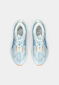 Light blue athletic shoes with a textured mesh upper, white laces, and an orange accent on the sole. Features zigzag patterns.