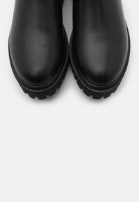 Black leather ankle boots with a rounded toe, textured surface, and thick, rugged sole, positioned side by side against a white background.