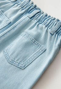 Svetlomodré džínsové nohavice s elastickým pásom, vybavené nášivkovým vreckom na zadnej strane a mäkkou, textúrovanou tkaninou.