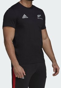 Mustan lyhythihaisen t-paidan valmistusmateriaali on puuvillasekoite, jossa on pyöreä kaula-aukko. Rintamuksessa on valkoinen Adidas-logo ja "All Blacks" -symboli.