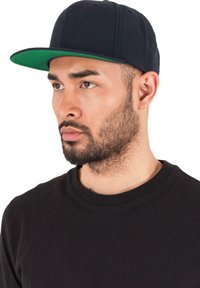 Căciulă de baseball neagră cu vizieră verde, având un design structurat, textură de fabrică netedă și închidere tip snapback.
