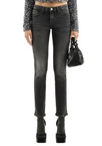 Czarne jeansy z wysokim stanem o dopasowanym kroju, z efektem sprania i delikatnym strzępieniem na końcach nogawek. Połączone z błyszczącymi sandałami na platformie.