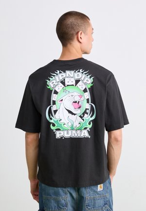 Man facing away wearing black shirt with roaring white panther graphic surrounded by green flames and "RIPNDIP" and "PUMA" text.