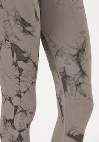 Leggings grises con un patrón de mármol negro, textura suave y costuras planas, con un diseño ajustado. Sin herrajes o acentos visibles.