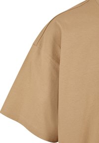 Beige bomulds-T-shirt med korte, brede ærmer. Stoffet er glat med en mat overflade, har en afslappet pasform og pæne sømme.