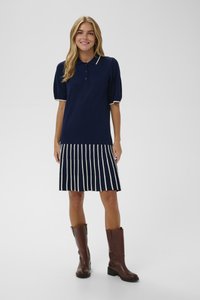 Tamsiai mėlynas polo suknelė su trumpomis pūkuotomis rankovėmis, raukinėta dryžuota sijonas ir kreminė apdaila. Dėvima su rudiem kelių ilgio batais. Lietaus tekstūra.