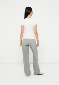 Haut blanc ajusté à manches courtes associé à un jean gris ample taille haute. Les jeans présentent un design classique à cinq poches et une coupe droite.