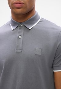 Hallhalline polo-särk klassikalise kraega, valge ääristuse ja väikese BOSS logo plaastriga rinnas. Valmistatud tekstureeritud kangast.