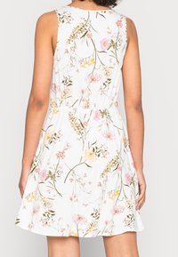 Floral dress with a white background, sleeveless design, gathered waist, featuring pink, yellow, and green botanical patterns. Smooth texture.