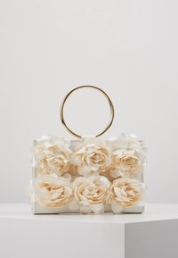 Sac à main blanc orné de fleurs artificielles douces de couleur crème, doté d'une poignée ronde en or et d'un design structuré. Texture lisse, pétales détaillés.