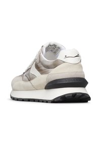 Sneaker con un mix di suede beige e pelle bianca liscia, dotato di una suola in gomma nera e un dettaglio di faccina sorridente sul tallone.