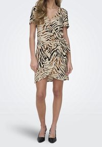 Robe croisée avec un motif rayé tigre, présentant des couleurs beige, noire et marron. Manches courtes, détail noué sur le côté et coupe au niveau du genou.