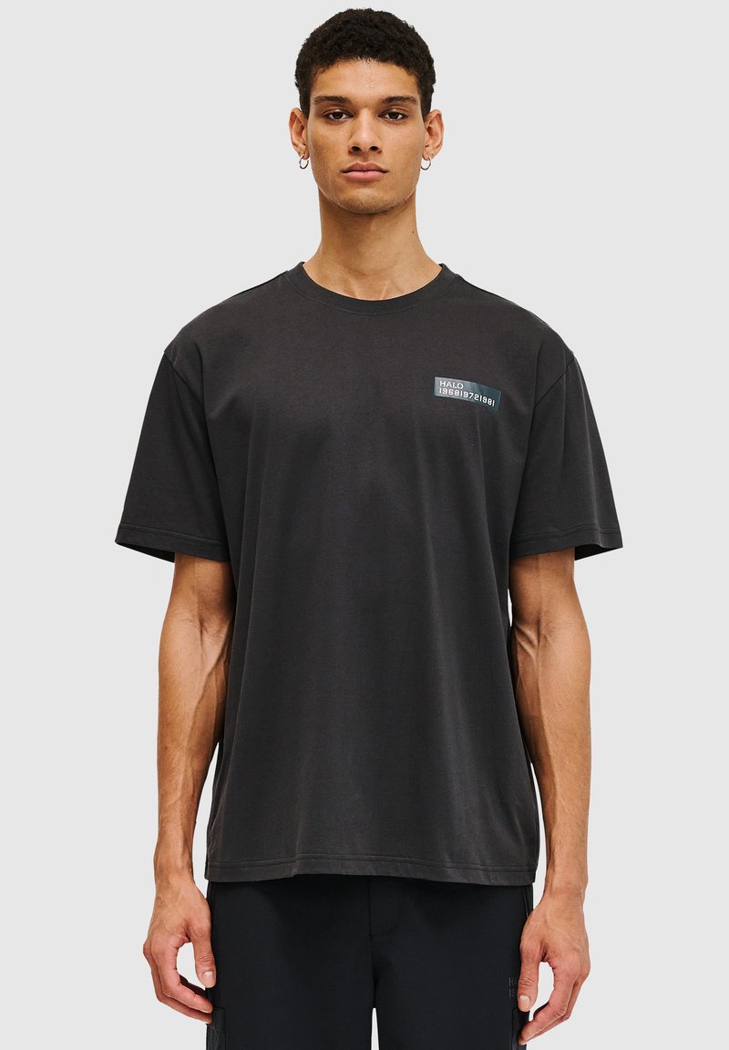 Zwart katoenen T-shirt met korte mouwen, ronde hals en een borstgraphic label met "HALO 1986". Glad textuur, relaxte pasvorm.