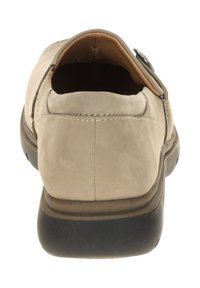 Beige leather shoe with a rounded back, rubber sole, and a smooth texture. Features stitching details and a button accent near the heel.