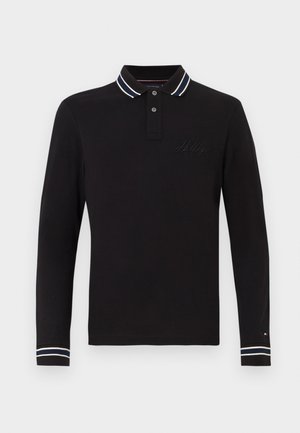 Melna garenogakla polo krekls, kas izgatavots no kokvilnas, ar divu pogu apkakli, kurai ir baltas un tumši zilas svītras, un ar izšūtu logo uz krūtīm.