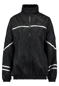 Chaqueta negra con cremallera y franjas plateadas reflectantes, cuello alto, puños elásticos y un dobladillo ligeramente fruncido. Confeccionada con un tejido brillante y suave.