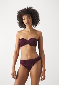 Bikini set in deep burgundy, featuring a strapless top with twisted design and high-waisted bottoms with a knot detail, made from smooth fabric.