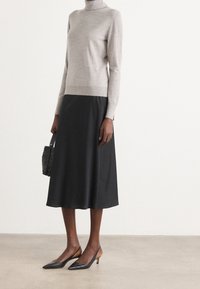 Jasnoszary sweter z golfem, czarna spódnica midi oraz czarne szpilki z brązowymi akcentami. Do stroju dołączona jest mała czarna torebka.