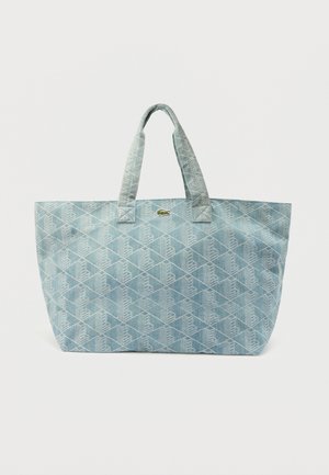 Bolso tote acolchado azul claro con patrón de diamantes, dos asas y un pequeño logotipo de cocodrilo verde en el centro delantero.
