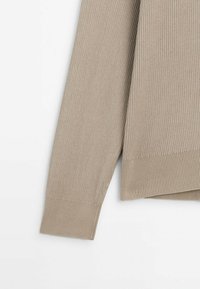 Beige gestrickter Pullover mit geripptem Muster, langen Ärmeln und einem leicht taillierten Saum für eine entspannte Passform.