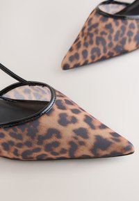 Leopárdmintás hegyes orrú, pántos női cipő áttetsző hálós felsőrésszel és fekete szegéllyel. A dizájn letisztult formát és texturált anyagot ötvöz.