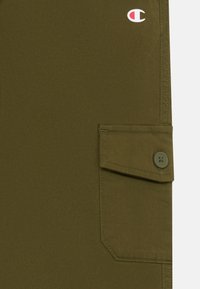 Olivengrønne shorts med en knaplukket klaplomme, lavet af et glat og holdbart stof. Har et lille, broderet logo på taljen.