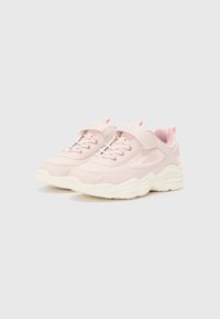 Une paire de baskets Fila rose clair avec des semelles épaisses blanches, des lacets et des bandes auto-agrippantes sur un fond gris clair.