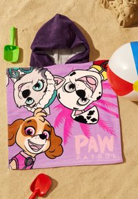 L'accappatoio con cappuccio della Paw Patrol presenta colorati cani dei cartoni animati su un tessuto morbido e vellutato di colore viola, con uno sfondo sabbioso e accessori da spiaggia nelle vicinanze.