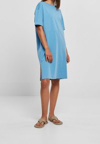 Jasnoniebieska bawełniana sukienka z krótkimi rękawami, luźny fason, z bocznymi rozcięciami i okrągłym dekoltem. W komplecie z beżowymi sandałami wsuwanymi.