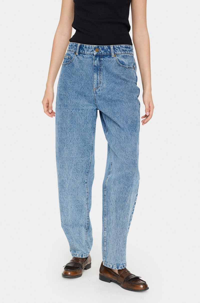 Svijetloplavi traperice s visokim strukom, ravnim nogavicama i izblijeđenom teksturom. Sadrži klasičan dizajn s pet džepova i zatvaranje na metalnu dugmad.