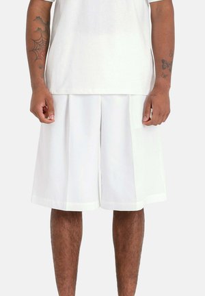 Shorts plissés blancs, en tissu léger, avec une texture lisse et une coupe droite qui tombe au-dessus du genou. Design simple.