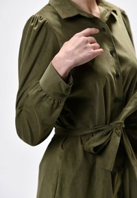 Oliivroheline nööbiga kleit, millel on seotud vöökoht, särgi krae, puffpikkade varrukatega ja tekstuuriga kangas, kus on mansetil nööbid.