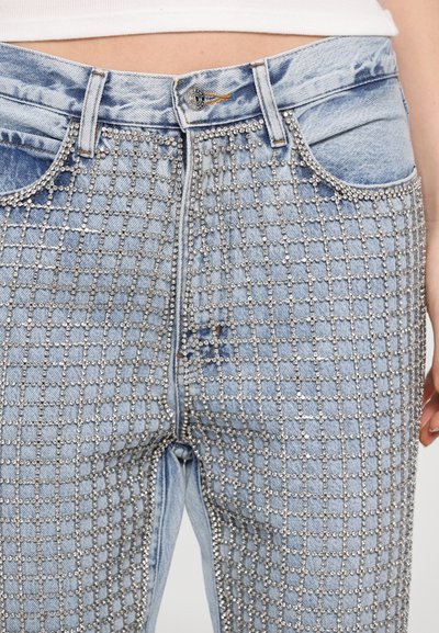 Light blue denim jeans featuring a grid pattern of silver studs along the front. Standard pockets and a zip fly are visible.