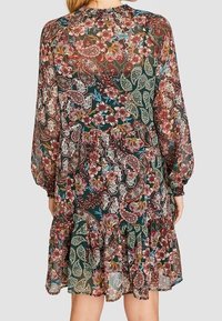 Vestido de tela ligera y transparente con estampado floral, que incluye mangas largas, un dobladillo con volantes y una mezcla de colores verde, rojo y blanco.