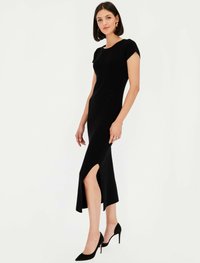 Czarna dopasowana sukienka z krótkimi rękawkami typu cap, rozcięciem do kolan i gładką fakturą. Nosi się z czarnymi szpilkami.