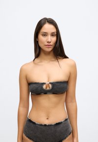 Top bikini bandeau negru cu decupaj cheie, cu dungi subțiri orizontale și cusături contrastante; asortat cu slipi înalți pe talie, de aceeași culoare.