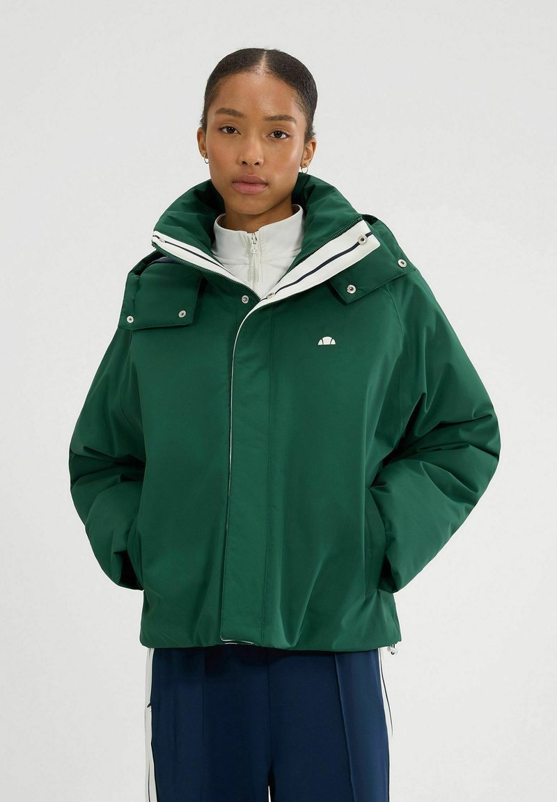 Zielona, doładowana kurtka z kapturem, zapinana na zatrzaski i zamek błyskawiczny, z białymi akcentami. Wykonana z gładkiego, trwałego materiału. Posiada dwie przednie kieszenie.