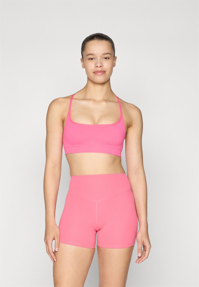 Top de sport rose court et short taille haute, fabriqués dans un matériau extensible et lisse. Dispose de bretelles étroites et d'une construction sans coutures.