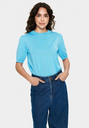 Top a maniche corte azzurro chiaro in maglia con scollo rotondo e una texture leggera, abbinato a jeans in denim scuro a vita alta.