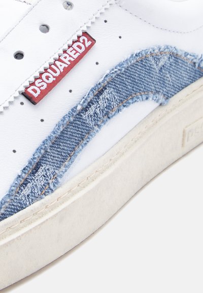 Baskets blanches avec perforations, détail vague en denim bleu, étiquette en tissu rouge DSQUARED2, et semelle texturée écrue.