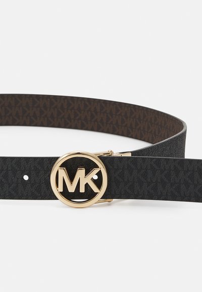 Ceinture réversible noire et marron en cuir texturé, dotée d'une boucle circulaire dorée avec le logo "MK" et d'un côté intérieur à motifs.