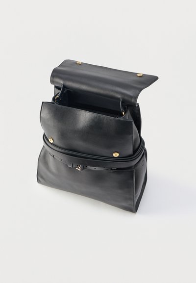 Μαύρη δερμάτινη τσάντα χειρός με ανοιχτό επάνω καπάκι, κλεισίματα με χρυσά κουμπιά και αφαιρούμενο ιμάντα ώμου, πάνω σε λευκό φόντο.